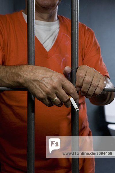 Ein Gefangener  der in seiner Zelle eine Zigarette raucht.