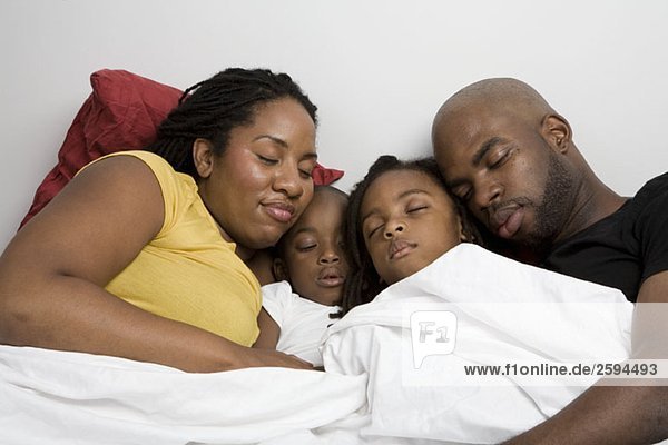 Eine vierköpfige Familie  die zusammen im Bett schläft.