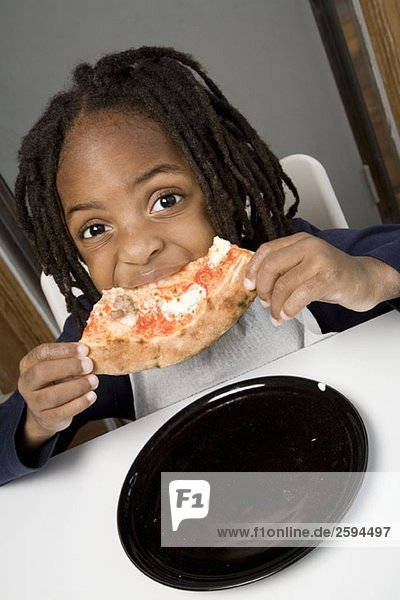 A young boy eating a slice of pizza