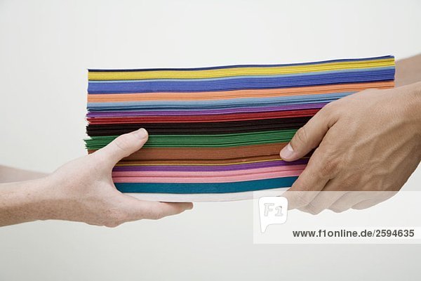 Menschliche Hände  die einen Stapel mehrfarbiges Papier austauschen