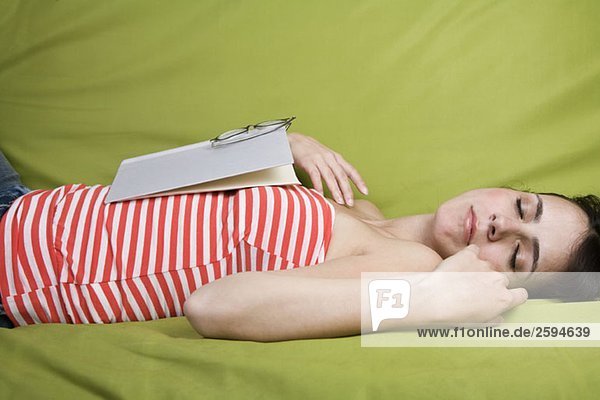 Eine Lateinamerikanerin schläft mit einem Buch auf der Brust.