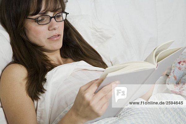 Eine Lateinamerikanerin beim Lesen eines Buches im Bett