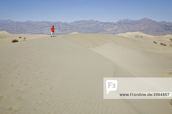 A person walking along a sand dune  Death Valley  California  USA