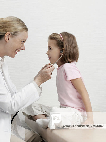 Eine Kinderärztin lässt ein Mädchen ihr Stethoskop benutzen.