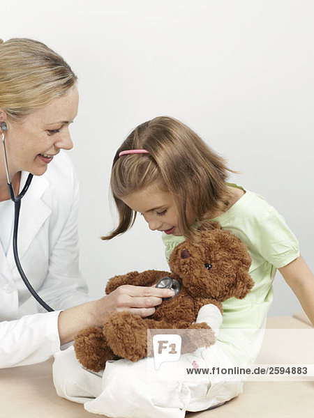Eine Kinderärztin untersucht den Teddybär eines Mädchens.