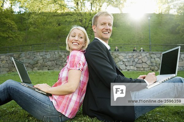 Guy and girl sitting in park using computer