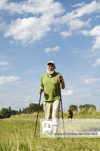 Älterer Mann zu Fuß mit Hund im Feld