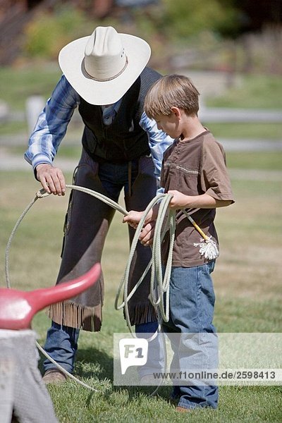 Man teaching boy to lasso  Lone Mt Ranch  Big Sky  Montana  USA
