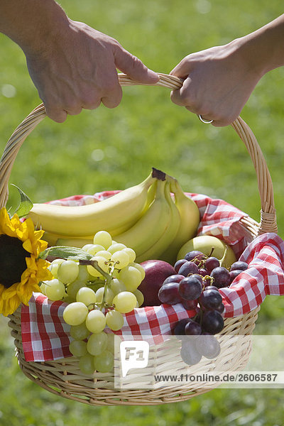 Junges Paar im Freien tragen gemeinsam Picknickkorb in der Hand Nahaufnahme