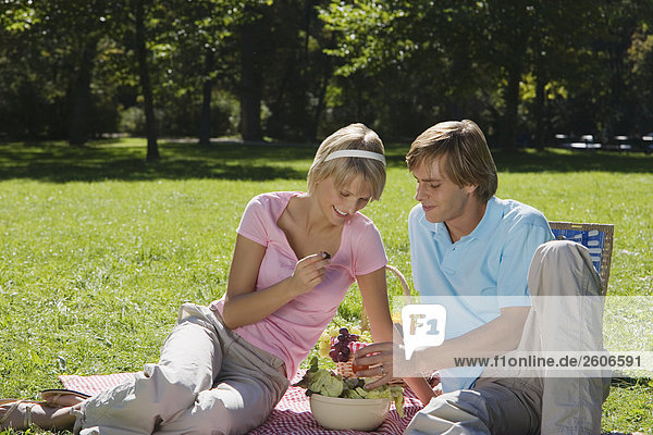 Junges Paar im Park beim Picknick essen Salat