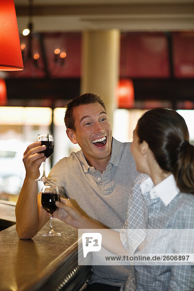 Lachendes Paar mit Rotwein flirtet an der Theke im Cafe Paris Frankreich