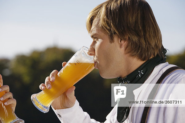 Junges Paar in Tracht trinkt Weizenbier Nahaufnahme von Mann und Hand der Frau