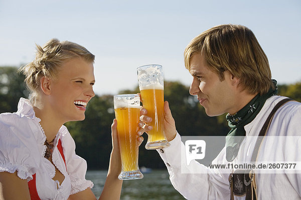Junges Paar prosten sich mit Weizenbier zu Biergarten am Seehaus Englischer Garten Nahaufnahme