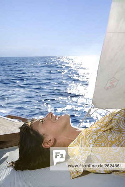 Frau liegt in der Sonne auf dem Segelboot