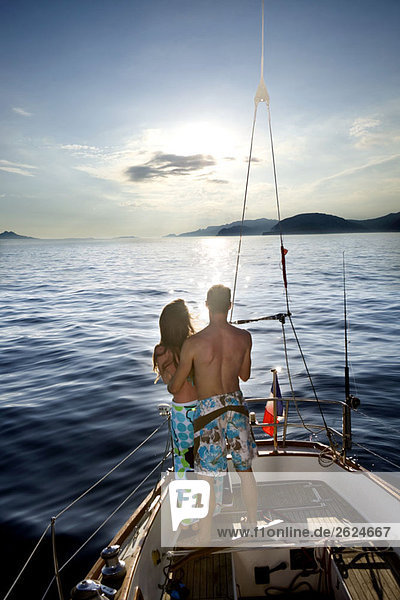 Paar beobachtet Sonnenuntergang auf einem Segelboot