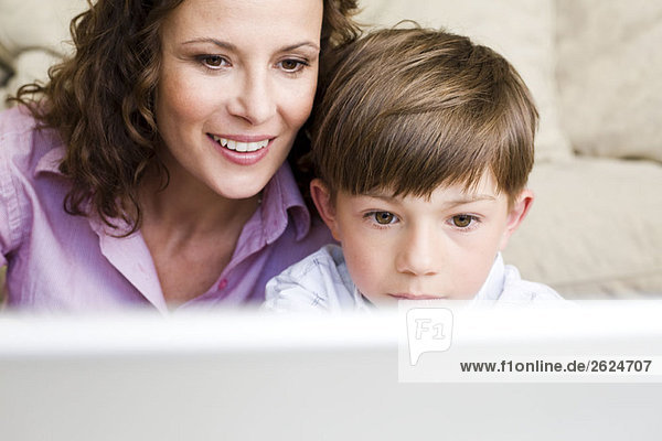 Frau und Sohn starren auf Laptop