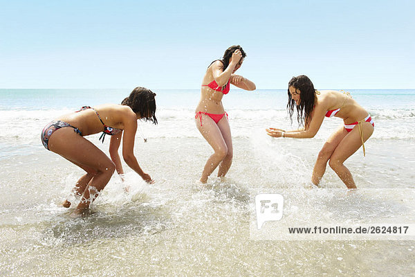 Three girls splashing each other