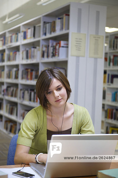 Young woman working on laptop in library