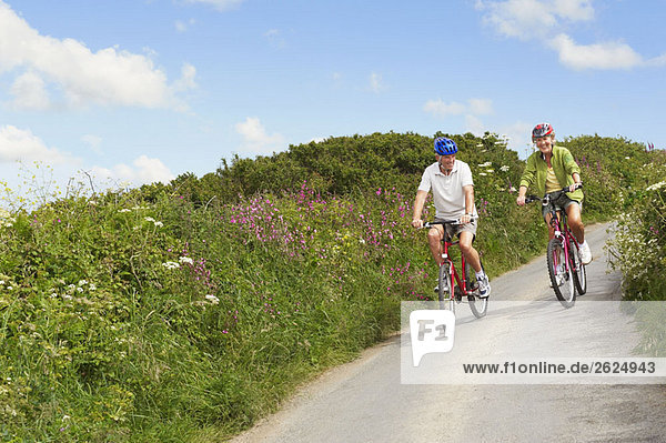Senior couple cycling down country lane