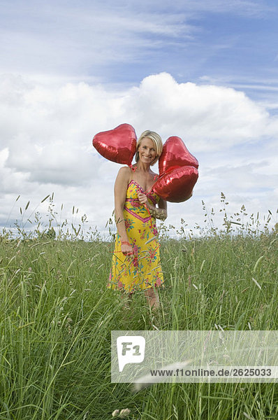 Lächelnde Frau im Feld mit Luftballons