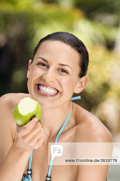 Junge Frau im Bikini mit Apfel  lächelnd  Nahaufnahme