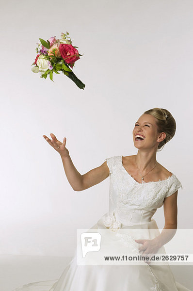 Junge Braut wirft Brautstrauß  lachend