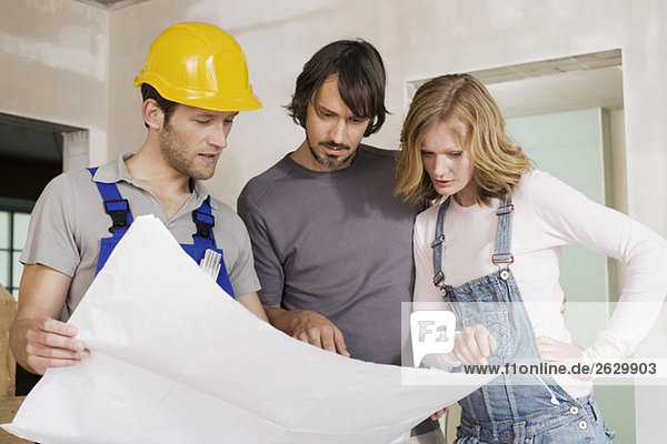 Young couple and construction worker looking at construction plan