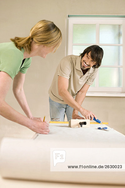 Young couple renovating  measuring wallpaper