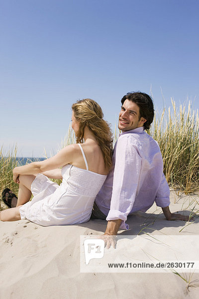 Deutschland  Ostsee  Junges Paar beim Entspannen auf der Grasdüne