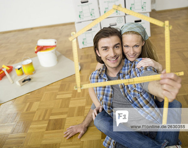 Young couple making house shape with folding rule  portrait