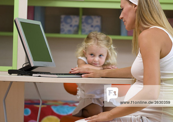Schwangere Mutter und Tochter (3-4)  mit dem Computer