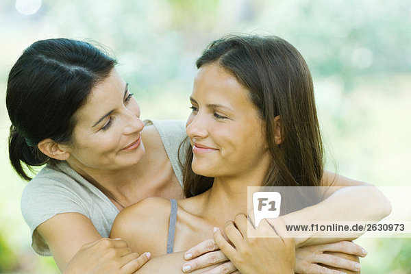 Mutter und Teenagertochter umarmend  einander anlächelnd  Portrait