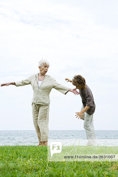 Großmutter hilft Enkel zu lernen  auf einem Bein zu balancieren.