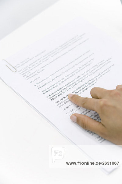 Hand zeigt auf Wort auf Dokument,  abgeschnittene Ansicht