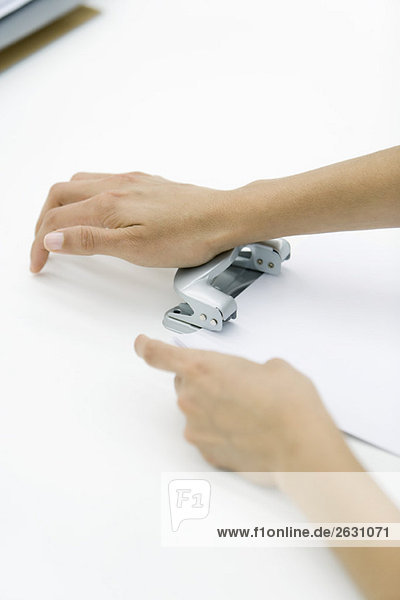 Hands using hole puncher