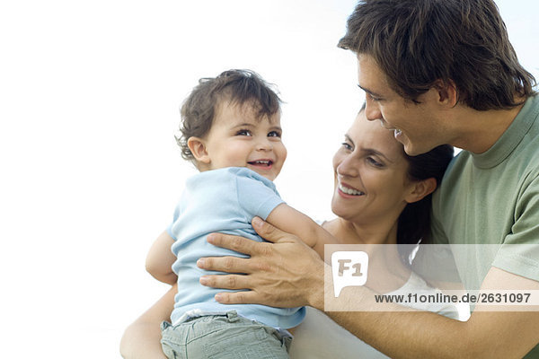 Eltern umarmen Kleinkind  alle lächelnd