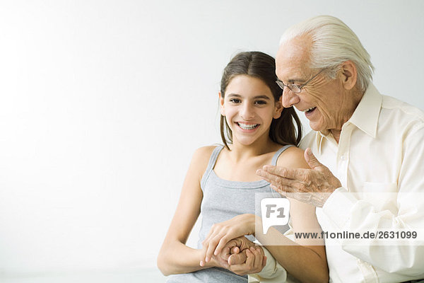 Großvater und jugendliche Enkelin Händchen haltend  lachend