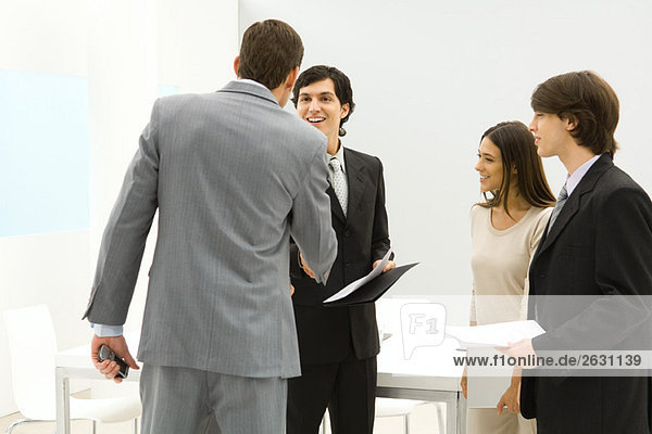 Professionals standing in conference room  businessmen shaking hands