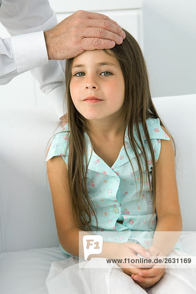 Arzt legt seine Hand auf die Stirn des kleinen Mädchens  Schnittansicht