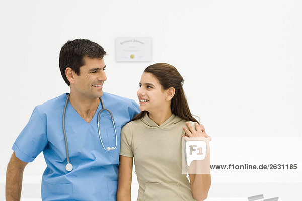 Doctor with arm around teenage girl's shoulder  smiling at each other