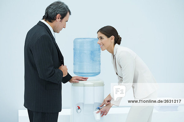 Zwei Profis plaudern neben dem Wasserkühler  Frau füllt Einwegbecher