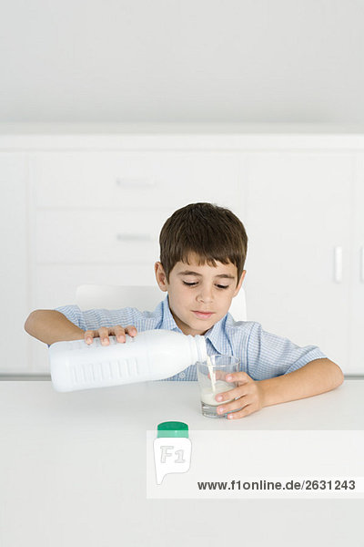 Boy pouring milk into empty glass