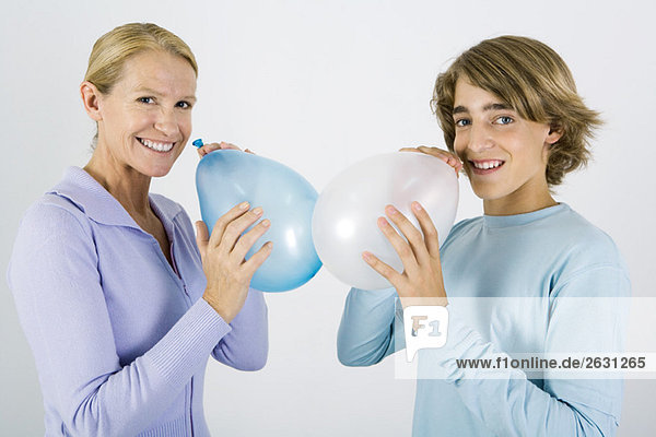 Mother and teen son inflating balloons  smiling at camera