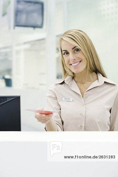 Professional woman holding out brochure  smiling at camera