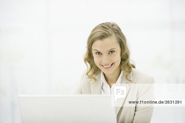 Professionelle Frau mit Laptop  lächelnd vor der Kamera