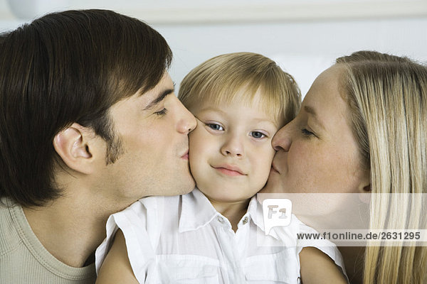 Parents kissing little boy's cheeks  boy looking at camera