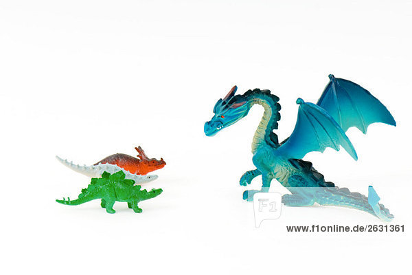 Spielzeugdrache vor drei kleinen Spielzeugdinosauriern