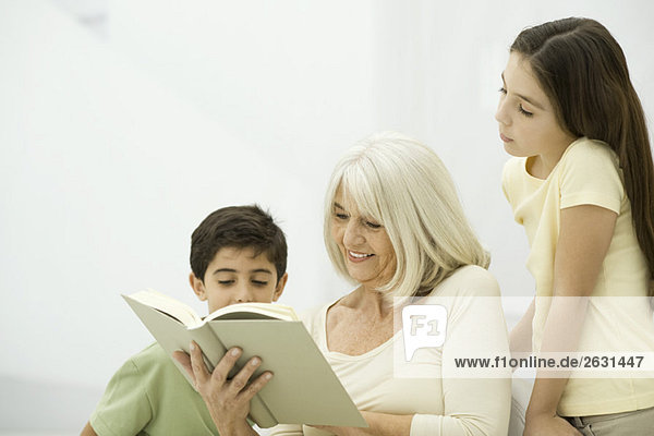 Großmutter und Enkelkinder lesen gemeinsam Buch