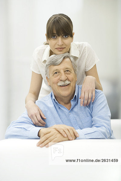 Woman resting chin on top of father's head  both smiling at camera  portrait