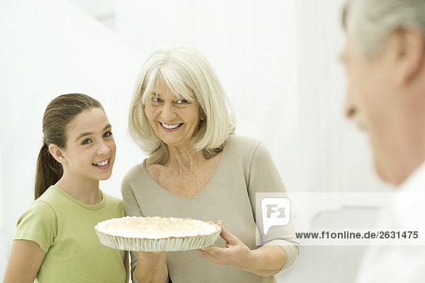 Grandmother and granddaughter side by side  senior woman holding pie